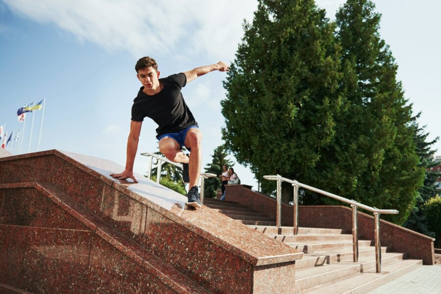 Above the obstacle. Young sports man doing parkour in the city at sunny daytime